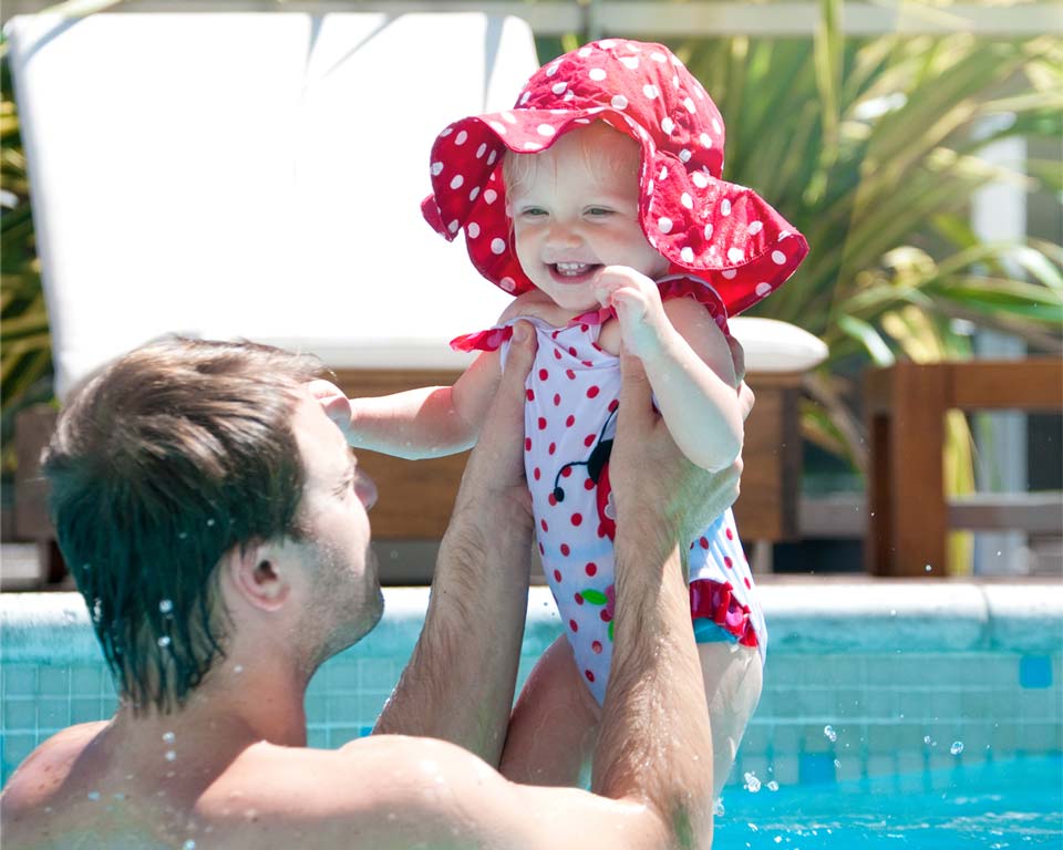 father holding toddler daughter in pool